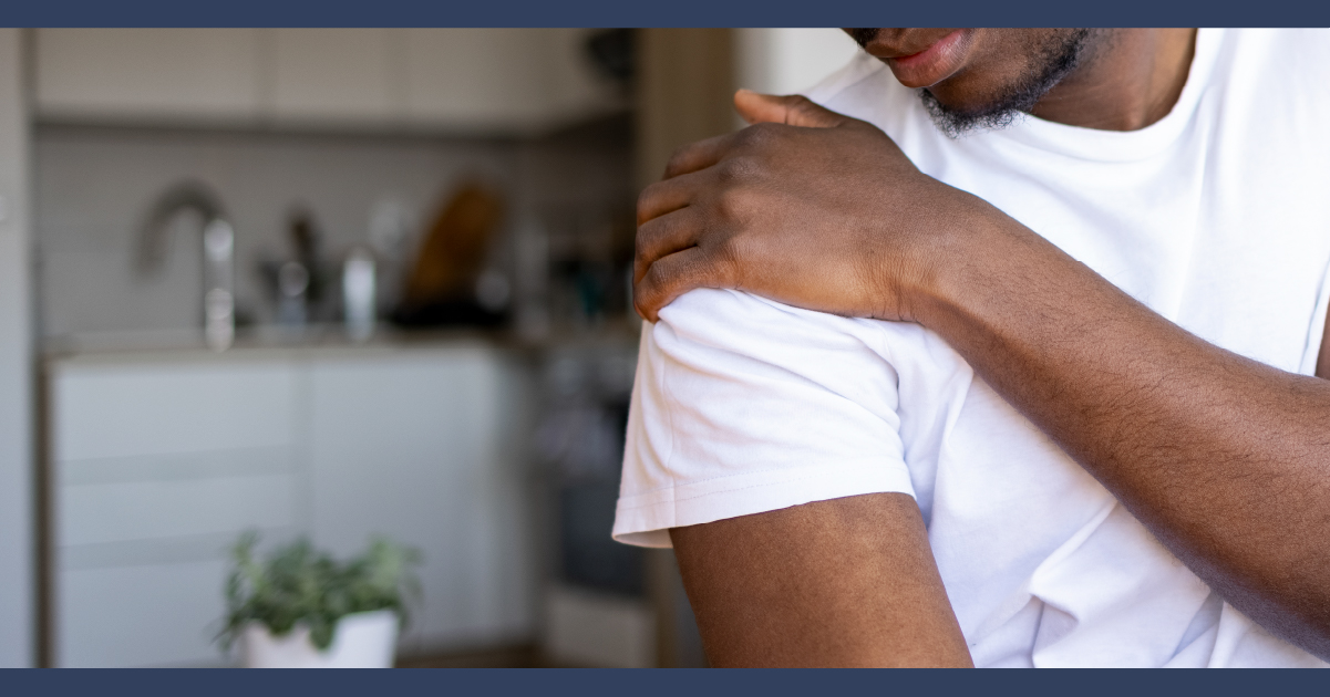 Man touching his shoulder with his hand, as if to massage the pain away