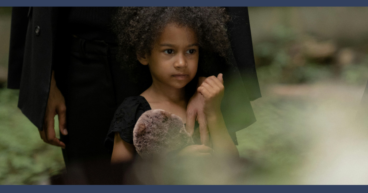 A child looking at the burial place of their loved one