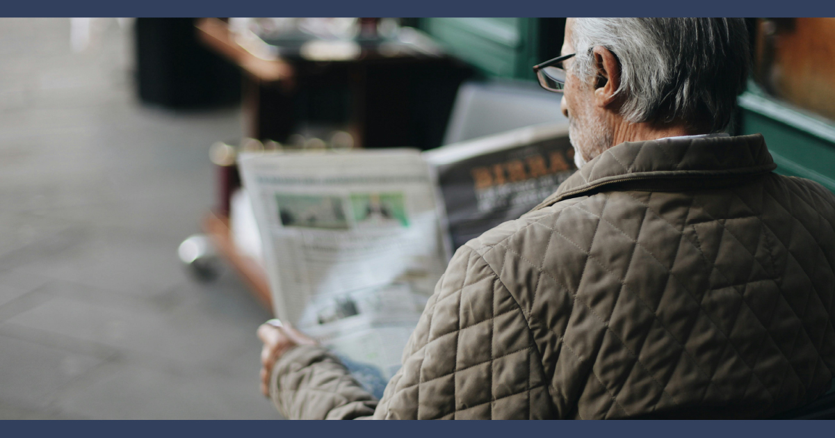 Elder reading newspaper alone