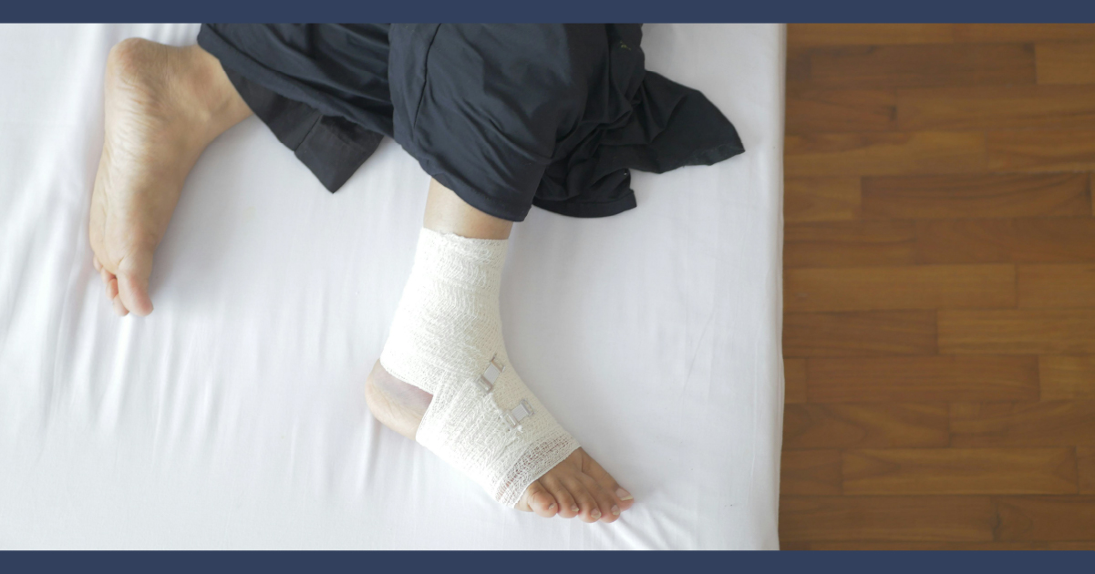 Person laying on bed with bandaged ankle