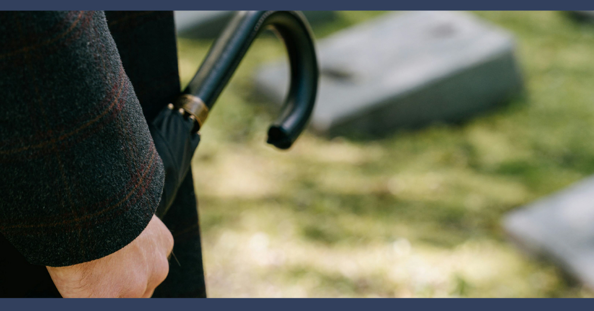 Man holding an umbrella at a funeral